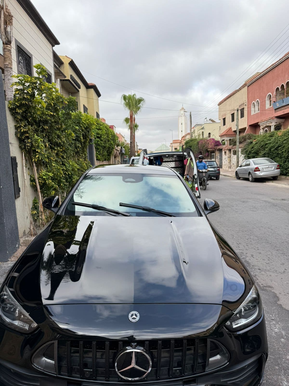 Sleek black Mercedes-Benz parked on a residential street, reflecting the overcast sky.
